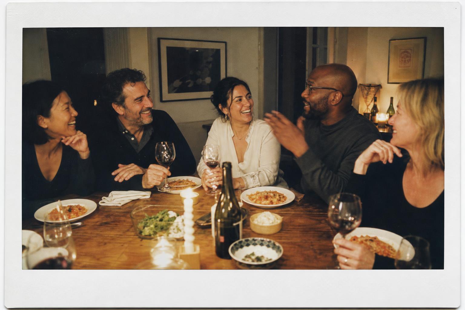 Friends laughing over a candlelit dinner party at home